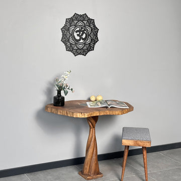 Small black OM mandala metal wall art above a live-edge pedestal table with a gray stool
