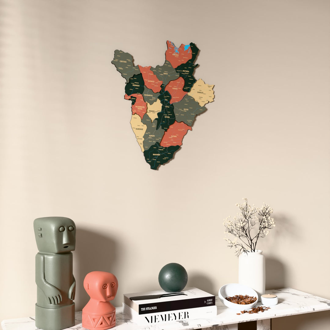 Sage Burundi wooden wall map on a beige wall above a console with figurines