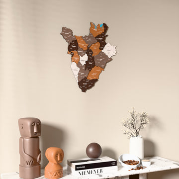 Soil Burundi wooden wall map on a beige wall above a console with figurines