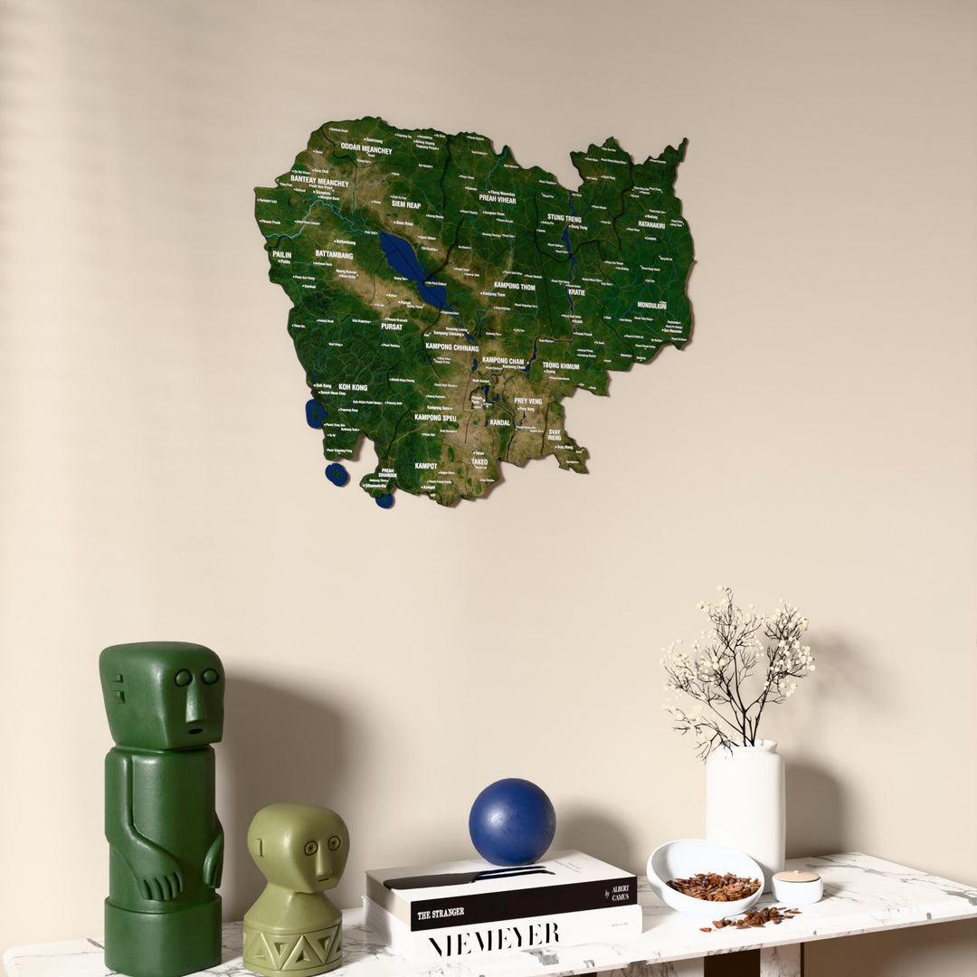 Satellite Cambodia wooden wall map on a beige wall above a console with figurines