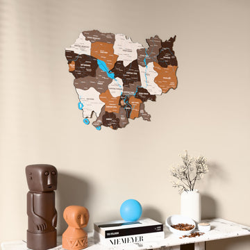 Soil Cambodia wooden wall map on a beige wall above a console with figurines