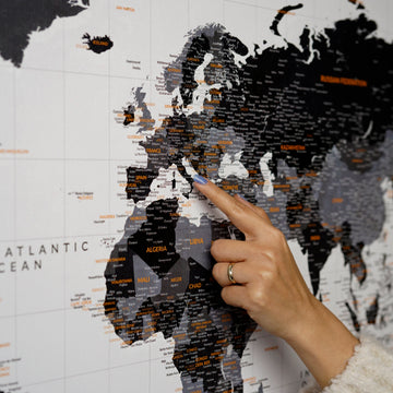 Close-up of Europe and North Africa on the black and gray canvas world map, with a hand pointing at Libya