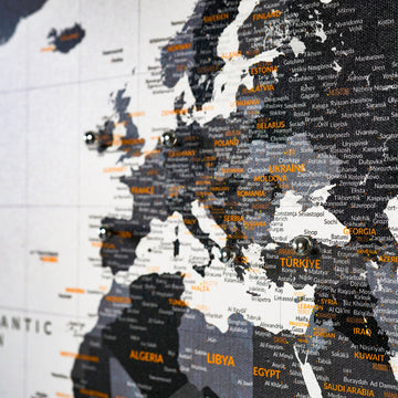 Close-up of Europe on the monochrome canvas world map, with metal pins and orange country labels