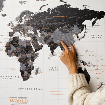 Monochrome canvas world map close-up with a hand pointing at Asia, country names and oceans in view