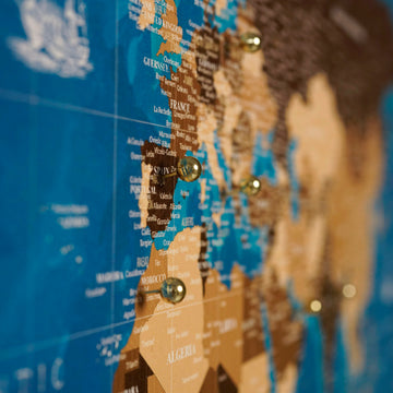 Close-up of Europe and North Africa on the navy canvas world map with gold pins in France and Morocco