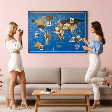 Navy blue ocean canvas world map with photos and string above a sofa, two women looking on