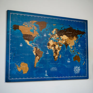 Navy blue ocean canvas world map with tan and brown countries on a light wall, angled view