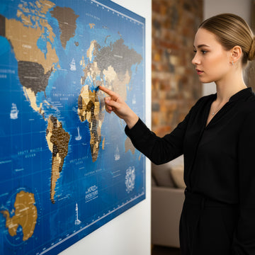 Navy blue ocean canvas world map hung on a white wall, a woman pointing at a spot