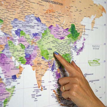 Watercolor world map canvas with purple, green and orange countries, a hand pointing at China and India