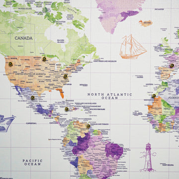 Close-up of North America and the Atlantic on the watercolor world map canvas, with gold push pins in the USA