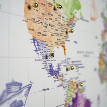 Blurred side-angle close-up of the USA and Central America on the watercolor canvas map with brass pins