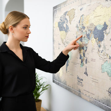 Muted vintage world map canvas with a compass rose on a wall, a woman in black pointing at Asia
