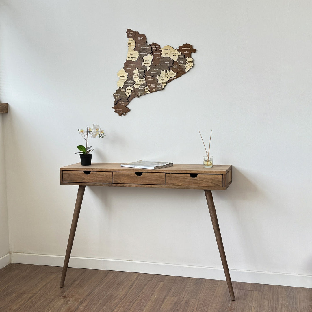 Wooden Catalonia wall map above a drawer console, angled view from the left near a window