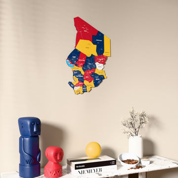 Flag colored Chad wooden wall map on a beige wall above a console with figurines