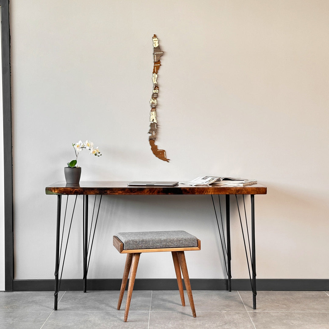 Tall wooden Chile map above a hairpin-leg desk with a gray upholstered stool