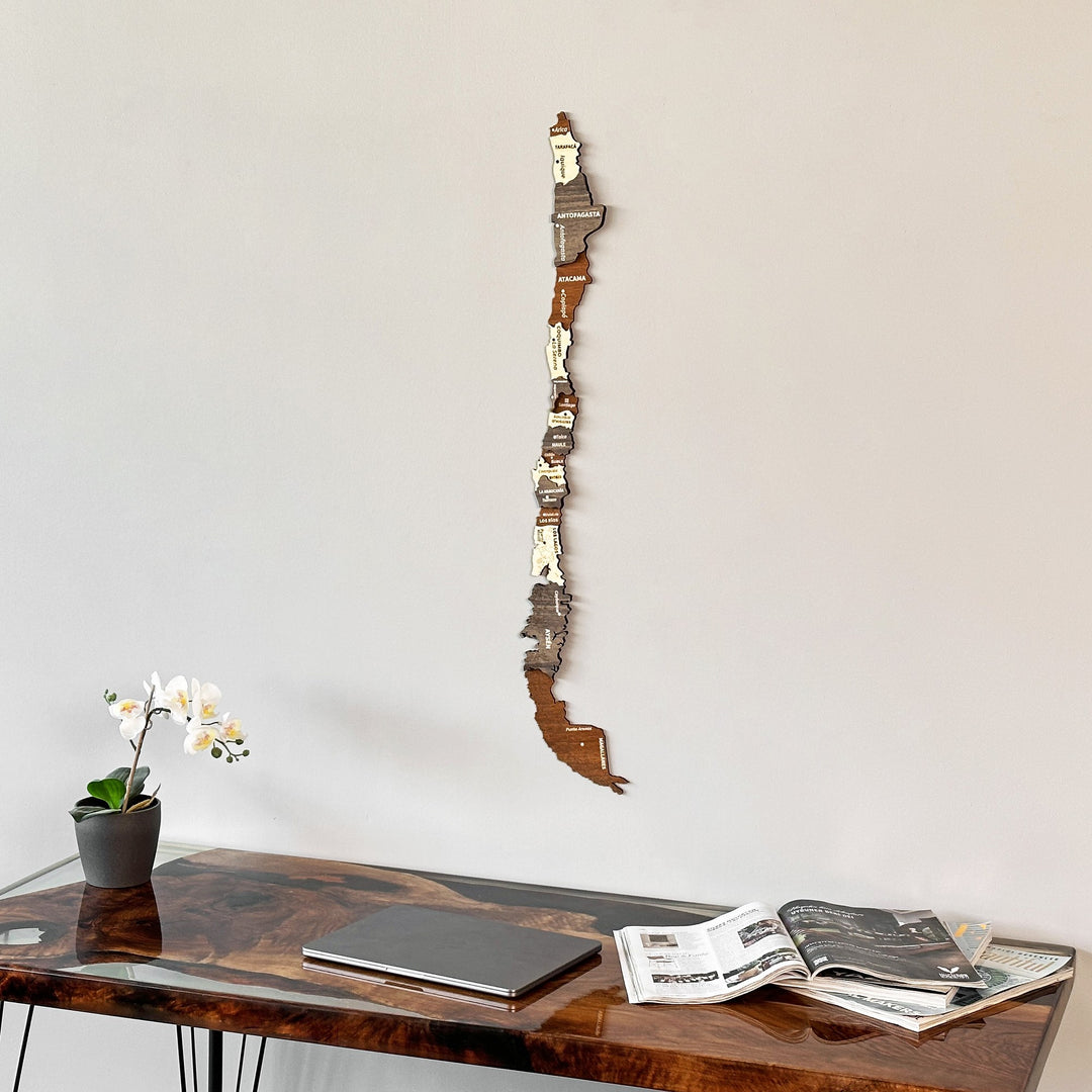 Wooden Chile map in the corner of a room above a desk with an open magazine