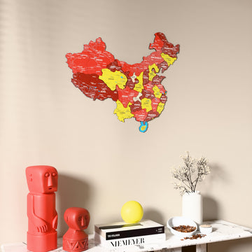Flag colored China wooden wall map on a beige wall above a console with figurines
