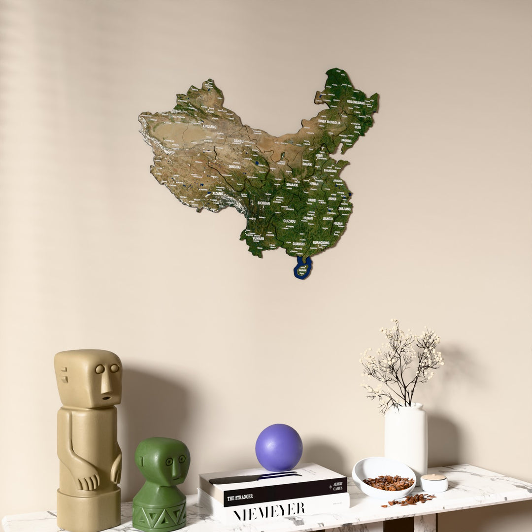 Satellite China wooden wall map on a beige wall above a console with figurines