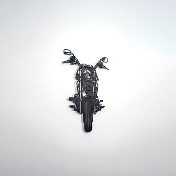 Black chopper motorcycle metal wall art on a white wall, wide shot
