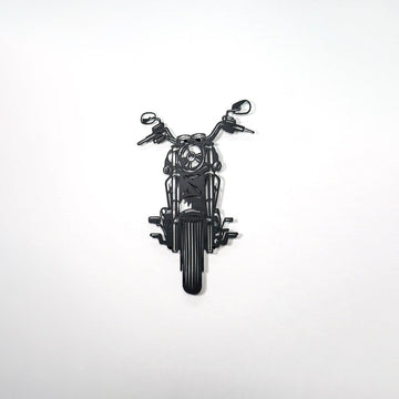 Black chopper motorcycle metal wall art on a large empty wall, from the right