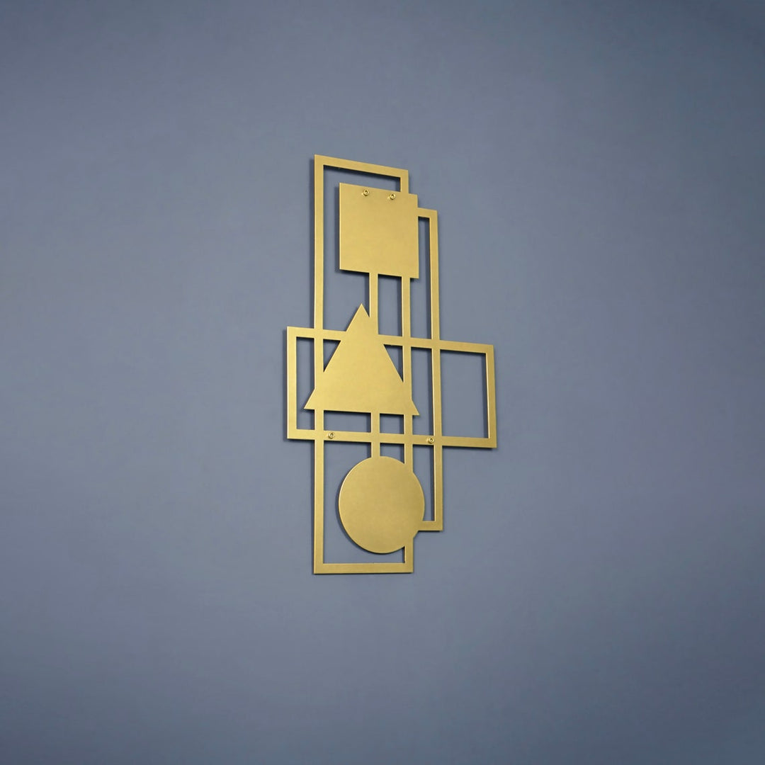 Gold geometric metal wall art on a blue-grey wall, wider shot
