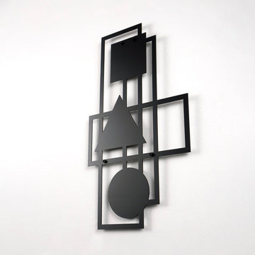 Black geometric metal wall art on a white wall, slight side view