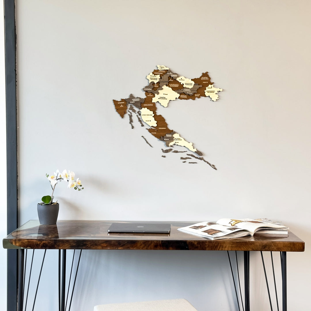 Croatia 3D wooden wall map in brown, gray and cream above a dark desk with an orchid
