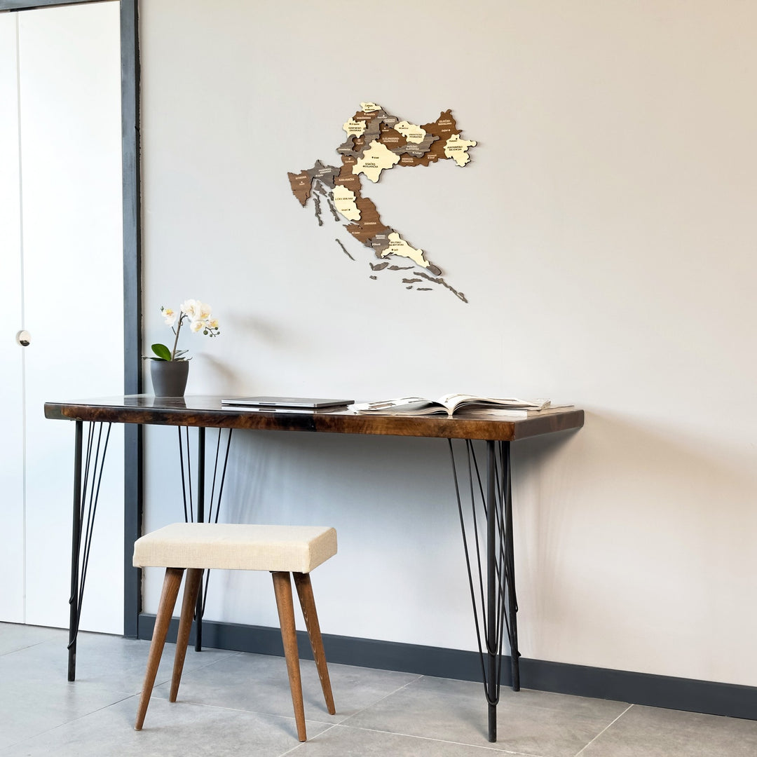Croatia wood map on a gray wall beside a white door frame, desk and stool below