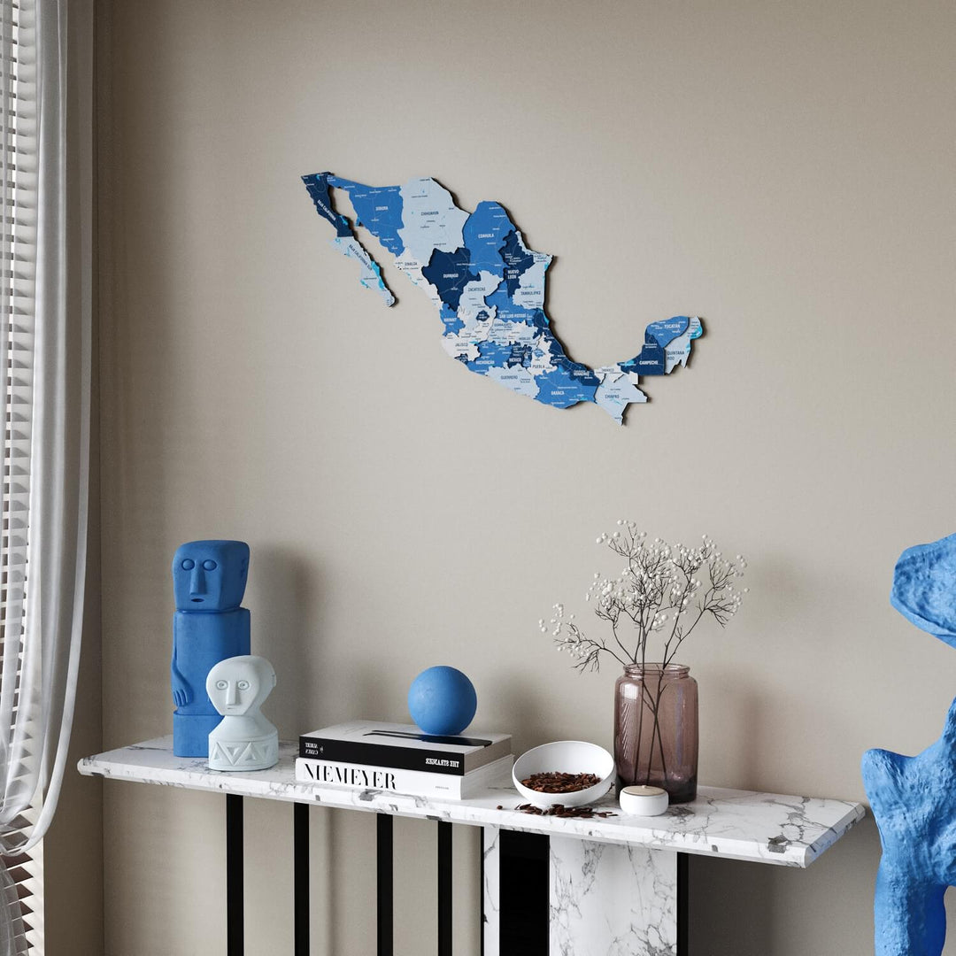 Navy Mexico wooden wall map in shades of blue above a marble console table, sheer curtain at the left