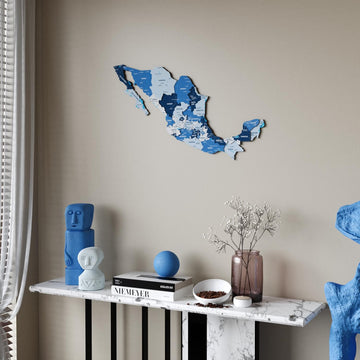 Navy Mexico wooden wall map in shades of blue above a marble console table, sheer curtain at the left