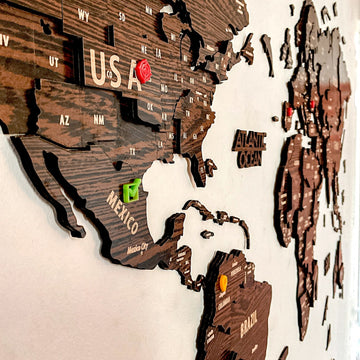 Close-up of the USA, Mexico and Colombia with colored push pins on the dark brown wooden world map