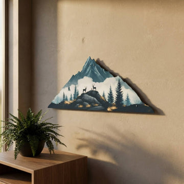 Deer and mountain metal wall art on a beige wall, side view next to a fern
