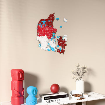 Flag colored Denmark wooden wall map on a beige wall above a console with figurines