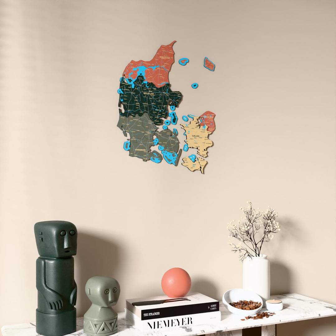 Sage Denmark wooden wall map on a beige wall above a console with figurines
