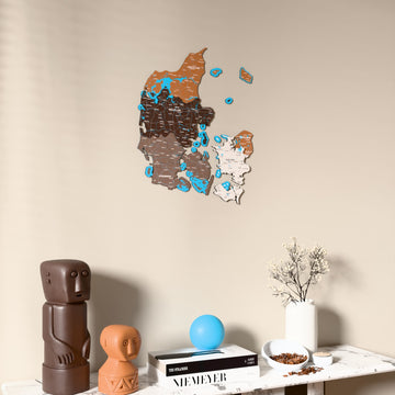Soil Denmark wooden wall map on a beige wall above a console with figurines