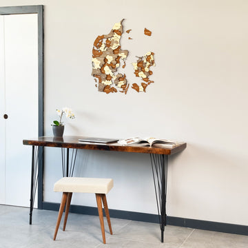 Denmark wooden wall map above a slim desk with a white door frame at left