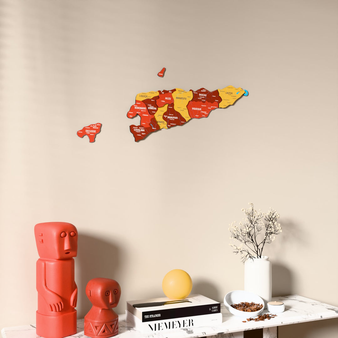 Flag colored East Timor wooden wall map on a beige wall above a console with figurines