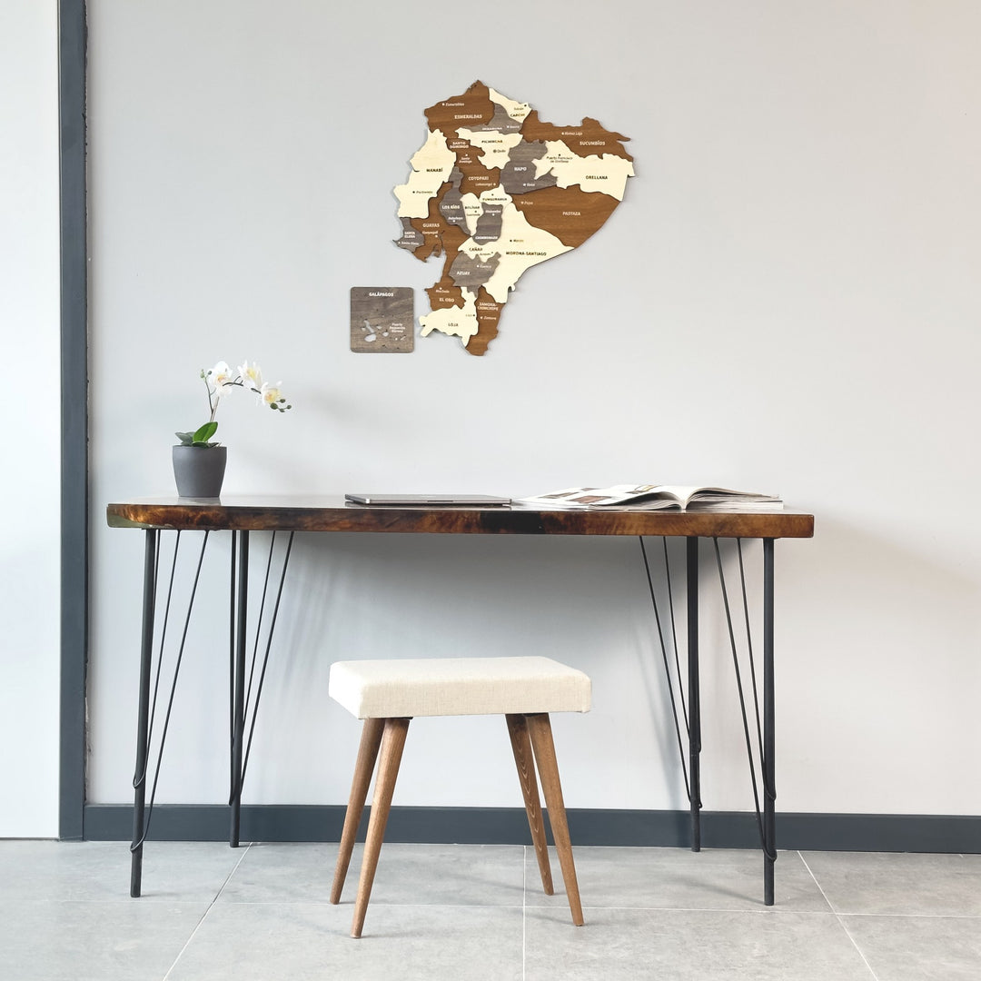 Wooden Ecuador map above a slim console desk with a white upholstered stool