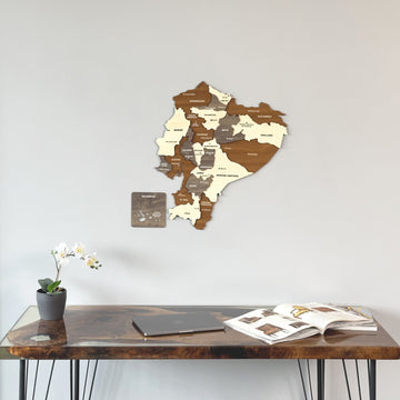 Wooden Ecuador map on a gray wall above a dark desk with a laptop
