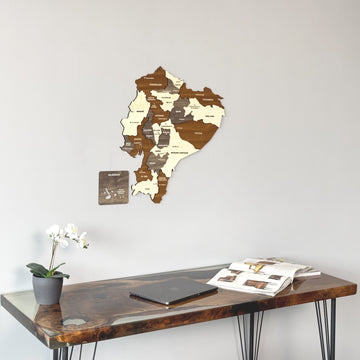 Wooden Ecuador map on a plain wall above a desk with an orchid, tight crop