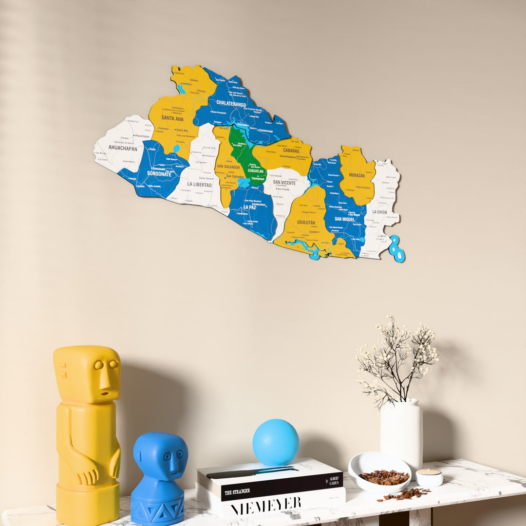 Flag colored El Salvador wooden wall map on a beige wall above a console with figurines