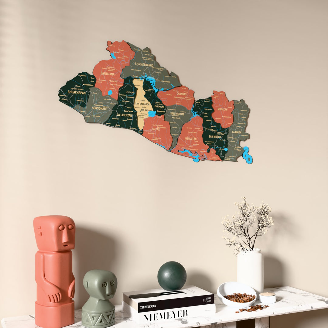 Sage El Salvador wooden wall map on a beige wall above a console with figurines