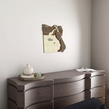 Small Egypt wooden wall map above a gray wood dresser with a decorative vase
