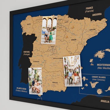 Angled close view of a black-framed Spain cork map with three pinned family photos and region names