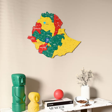 Flag colored Ethiopia wooden wall map on a beige wall above a console with figurines