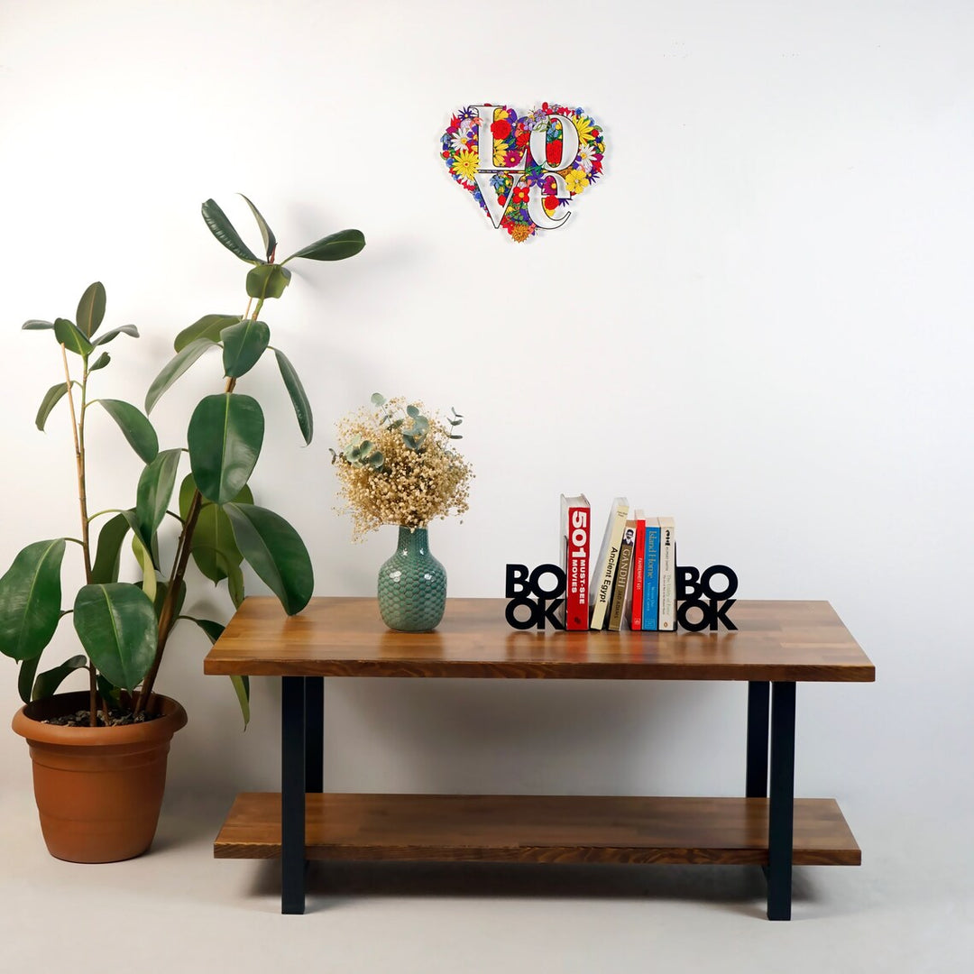 Floral LOVE heart metal art on a white wall above a wooden console with books