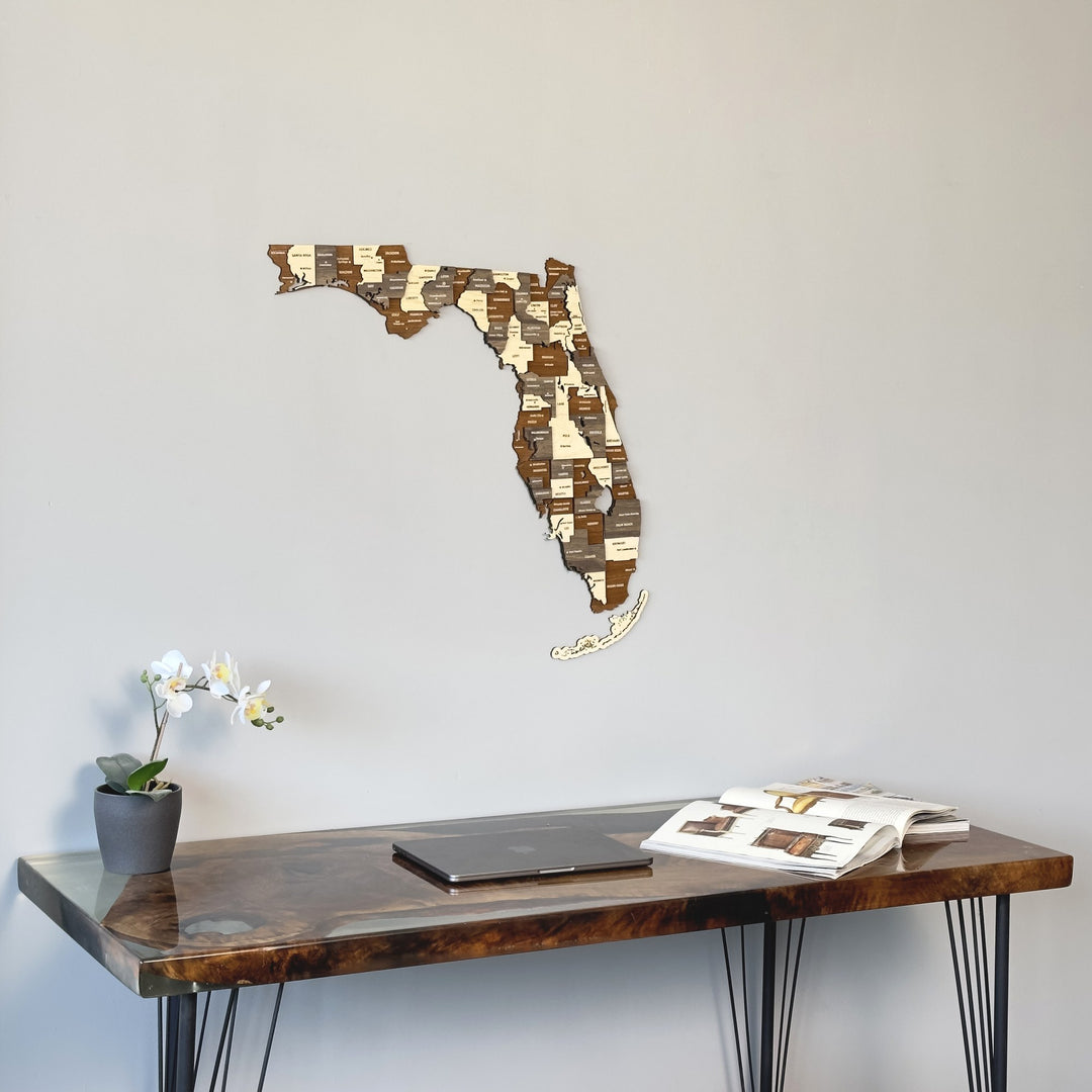 Multicolor wooden Florida map on a gray wall above a dark desk, seen from the left