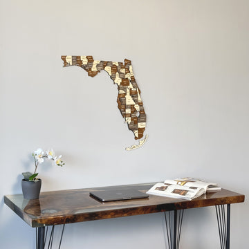 Multicolor wooden Florida map on a gray wall above a dark desk, seen from the left
