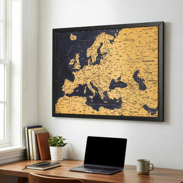 Framed cork map of Europe seen from the side above a wooden desk with a laptop