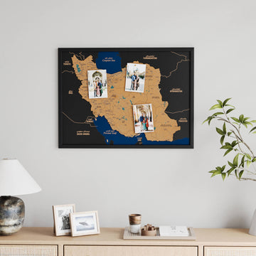 Black-framed landscape Iran cork wall map with three pinned travel photos above a wooden sideboard